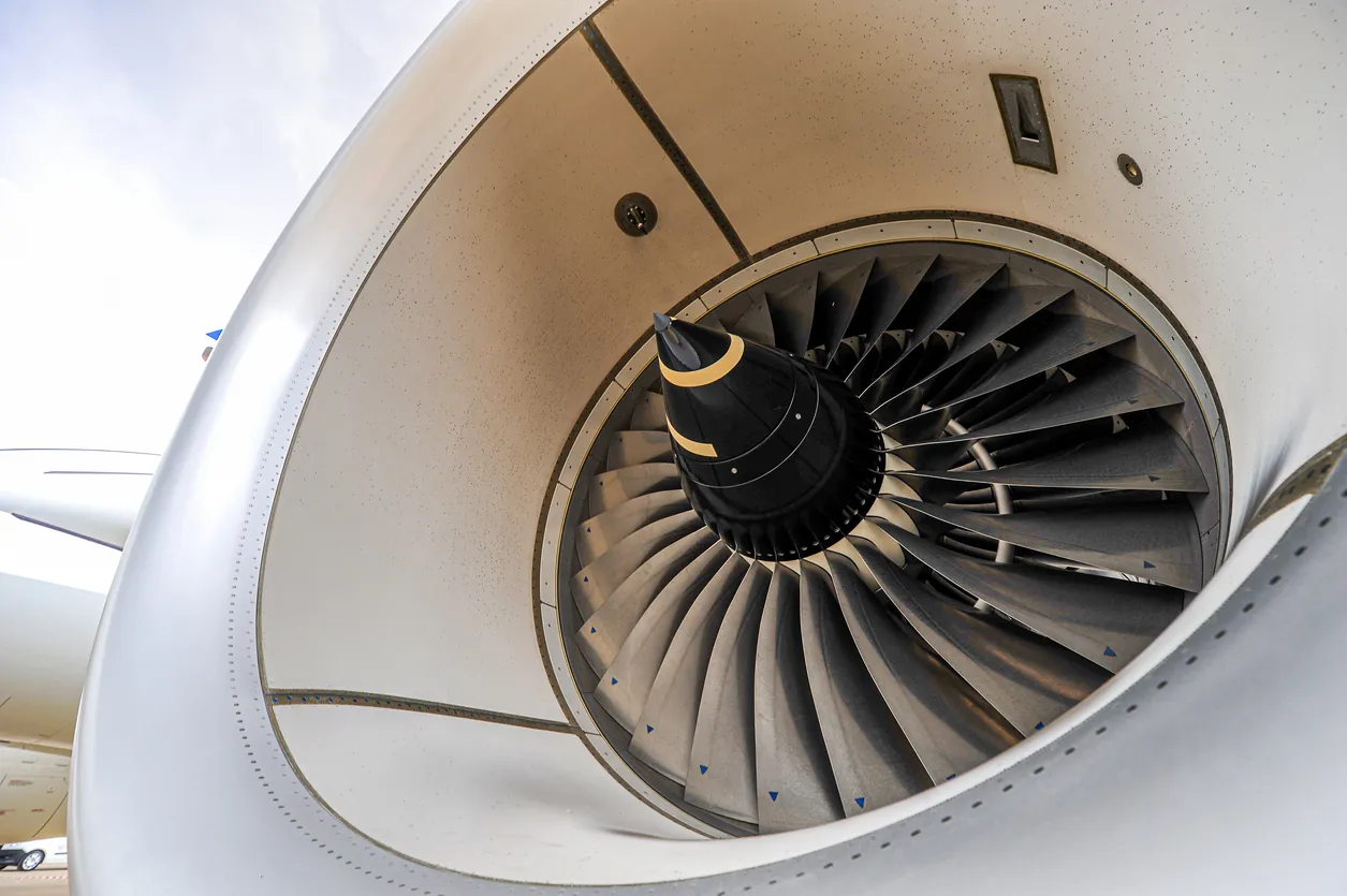 Gros plan sur les pales d’un turboréacteur d’avion, vue depuis l’avant, mettant en évidence la structure aérodynamique du moteur.