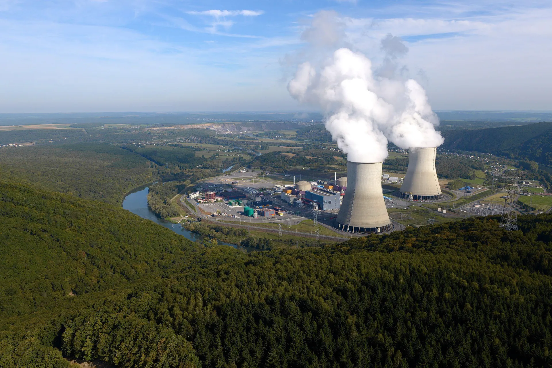 Vue aérienne d’une centrale nucléaire avec ses tours de refroidissement émettant de la vapeur.